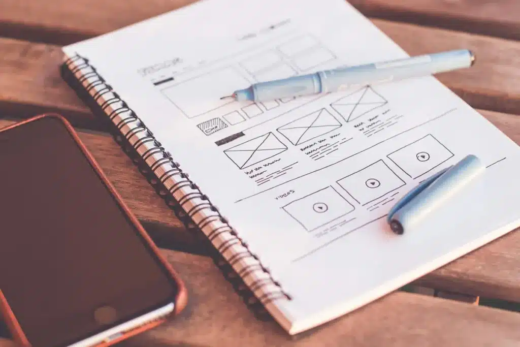 Carnet de wireframes de site web avec stylo et smartphone, début de conception