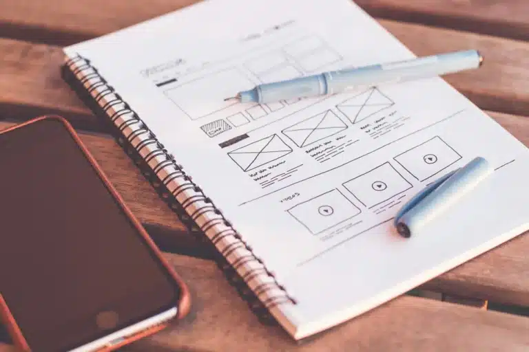 Carnet de wireframes de site web avec stylo et smartphone, début de conception
